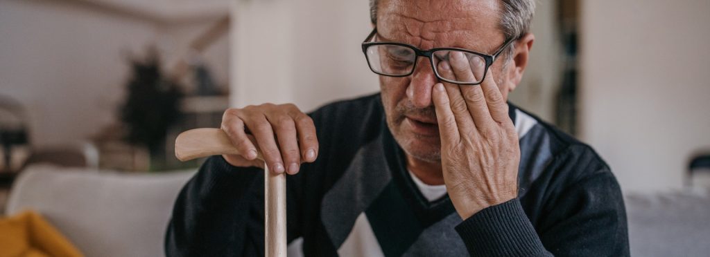 older man rubbing one eye due to cataracts
